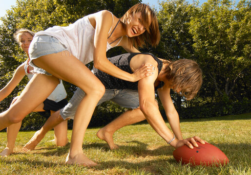 Young adult friends and family playing backyard rugby
