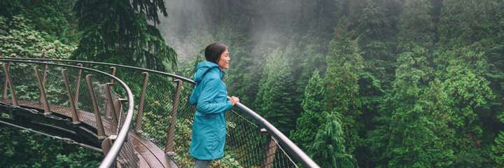 Canada Autumn travel destination in British Columbia. Asian tourist woman walking in famous attraction Capilano Suspension Bridge Park in North Vancouver. Canadian vacation banner.