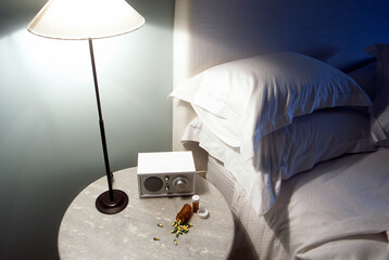 Lamp switched on resting on bedside table next to bed