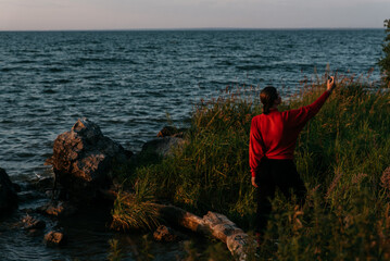 Photo  of a Summer Camping Activity. Travel location of popular tourist outdoor. View of beautiful Sea Landscape and Woman make selfie. Vacation by the lake in a camp with a bonfire and tent