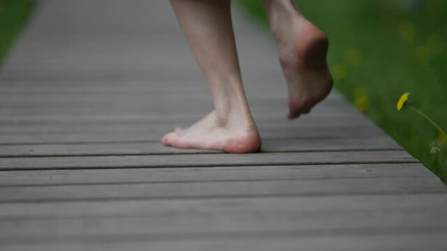 female bare feet walk along a wooden path and bounce. close-up. small depth of field