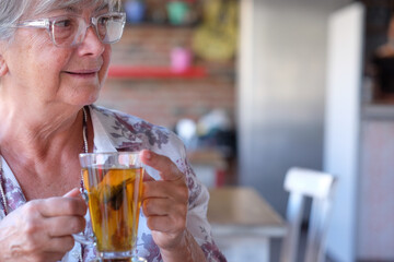 Portrait of beautiful elderly woman in coffee shop, enjoying herbal tea. Senior gray-haired people