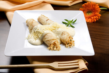 Panquecas com recheio de frango desfiado com molho bechamel e queijo parmesão, em prato branco no...