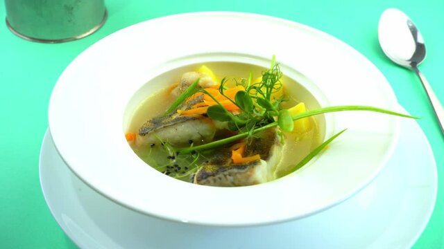 Fish soup - ukha. Lunch in a white deep plate. Fish food on the table. Potatoes, carrots, onions, broth. Fish meat Pike perch. The plate is spinning. Healthy and tasty. Restaurant serving