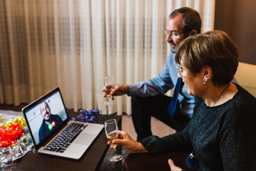 Senior hispanic couple having a video call through laptop with their son at christmas holidays -...