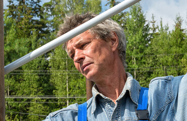 Male Builder with a tape measure on a real construction site in nature. Measures the distance...