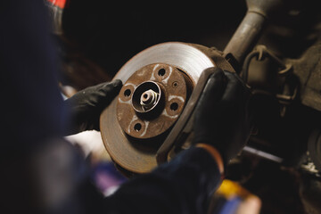 Hands of mixed race female car mechanic wearing overalls, preparing car using angle grinder