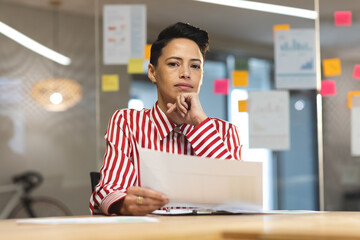 Thoughtful caucasian female business creative brainstorming and writing memo notes on glass wall