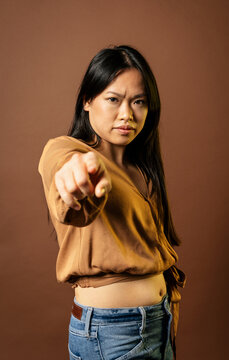 Serious Asian woman pointing at camera