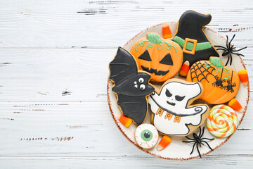 Halloween gingerbread cookies with candies and spiders on white wooden table