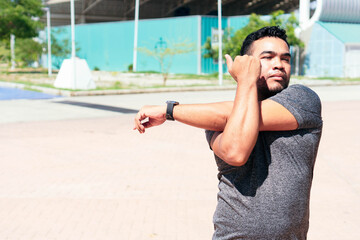 Latino man stretching his arm and warming up for training.