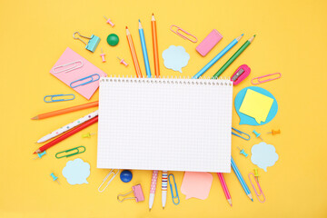 School supplies and notepad with space for text on yellow background