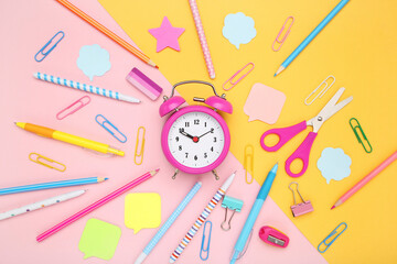 School supplies with alarm clock on colorful background