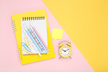 School supplies with alarm clock on colorful background