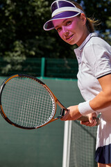 Confident Young Caucasian Lady In White Uniform And Cap Holding Tennis Racket In Hands, Smiling, Motivated Sportswoman On Hardcourt At Summer Day. People Lifestyle, Fitness, Sport Concept