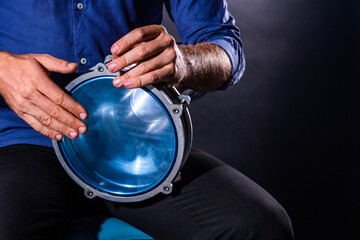 Closeup drummer male hands with drum. Man is drumming on metallic blue percussion musical instrument. Musician is playing live ethno rhytm music. Summer festival performance concept. Modern art.