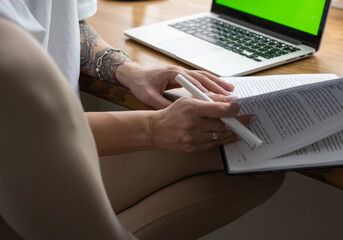person working on laptop with book and pencil