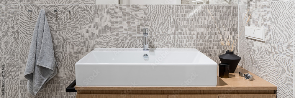 Wall mural Close-up on washbasin in bathroom with modern, patterned tiles, panorama