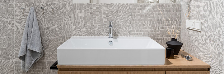 Close-up on washbasin in bathroom with modern, patterned tiles, panorama