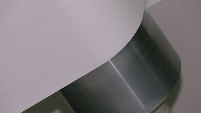 Close-up view of paper roll mechanism of professional wide format printer with white paper loaded inside. Blank paper roll in large printer format inkjet machine for industrial business.
