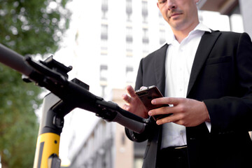 Man holding mobile phone in hands, paying for electric scooter outdoor and ready to go. close-up photo of hands, male in formal wear. modern technologies, devices, smart vehicle, peopel lifestyle