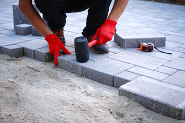 The master in yellow gloves lays paving stones