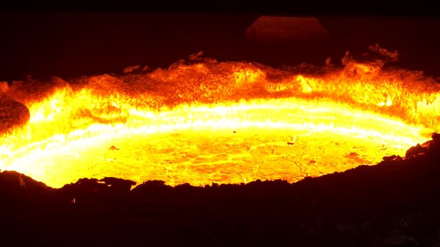 Hot metal in factory. The surface of a hot liquid slag in a metallurgical ladle. Thick crust covered with trash net.
