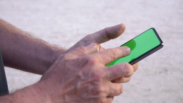  hand with cell phone outdoors green screen
