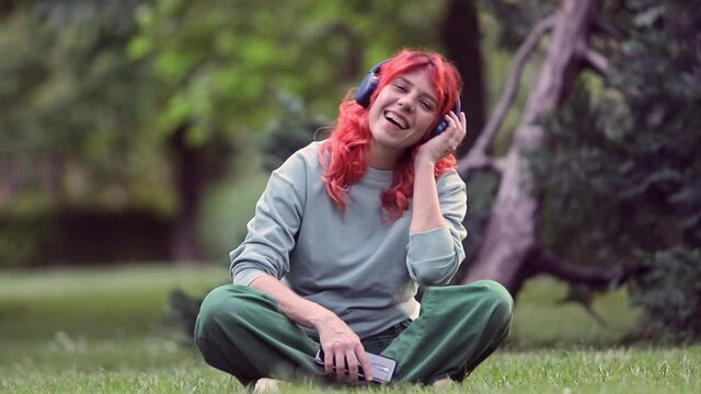 woman smailing  with headphone sitting at the parck