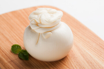 Delicious fresh cheese made from cream and milk - burrata. Italian tender cheese with herbs on a light background