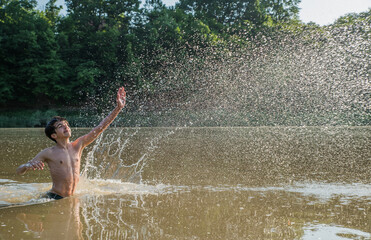 Teenager splashes water in the river.