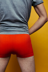 A sporty LGBT guy in tight colored boxers poses against a background of colored paper. body parts:...