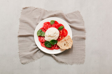 Delicious fresh cheese made from cream and milk - burrata. Italian tender cheese with tomato and greens salad, bread and olive oil.