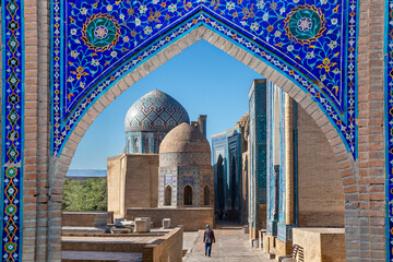 View over the mausoleums and domes of the historical cemetery of Shahi Zinda through an arched gate, Samarkand, Uzbekistan - obrazy, fototapety, plakaty
