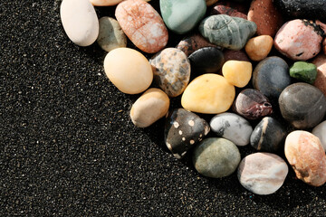 Sea stones, on black healing, magnetic sand, close-up. Background, texture for postcards, resort, health resort for joint diseases