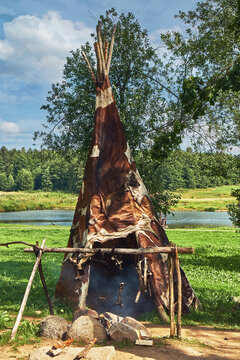 Indian wigwam covered with cow skins, bonfire and spit in the shade of trees