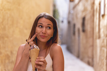 young woman eat ice cream in a narrow alley in Mdina, Malta