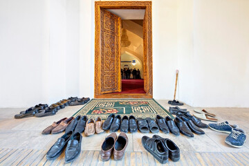 Shoes taken off to get in the mosque with people praying in the background, Samarkand, Uzbekistan