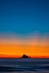 Haystack rocks silhouette against colorful sunset evenings on the beach
