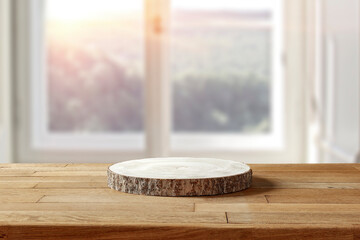 Wooden pedestal on a wooden table in an interior with sun rays 