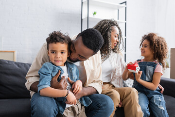 happy african american family sitting on sofa in new apartment