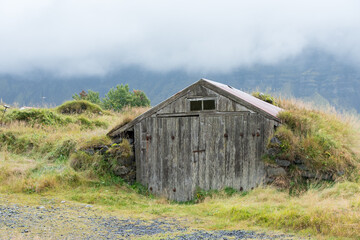 Fototapeta na wymiar alte Holzhütte im Grashügel im Nebel