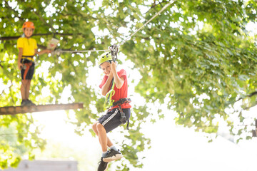 Adventure climbing high wire park - little boy on course in mountain helmet and safety equipment