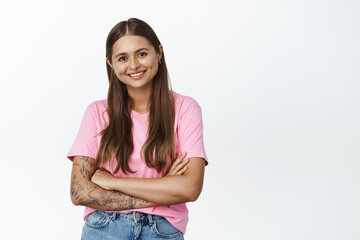 Young happy woman smiling, standing in relaxed natural pose, cross hands on chest and looking confident at camera, white background