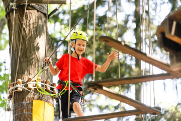 Cute school boy enjoying a sunny day in a climbing adventure activity park