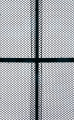 Metal chain link fence pattern straight on. Silhouetted by sky.