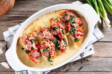 Chicken breast in creamy garlic sauce in baking dish on a wooden table. Healthy diet food. Top view, flat lay