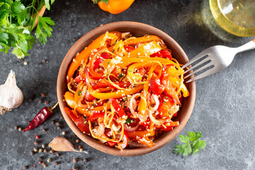 Sweet peppers with carrots, sesame seeds and vegetables in a bowl on a dark background. Top view