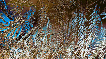 Fantasy ice crystals. Drawing of frost on window glass. A pattern of leaves and stems of magical fantastic plants. Abstract mystical brown and blue background. Fiery winter wallpaper. Macro