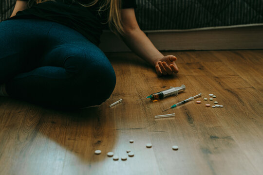 Addict woman with syringe and drugs on the floor. Substance abuse, drugs addiction concept. 